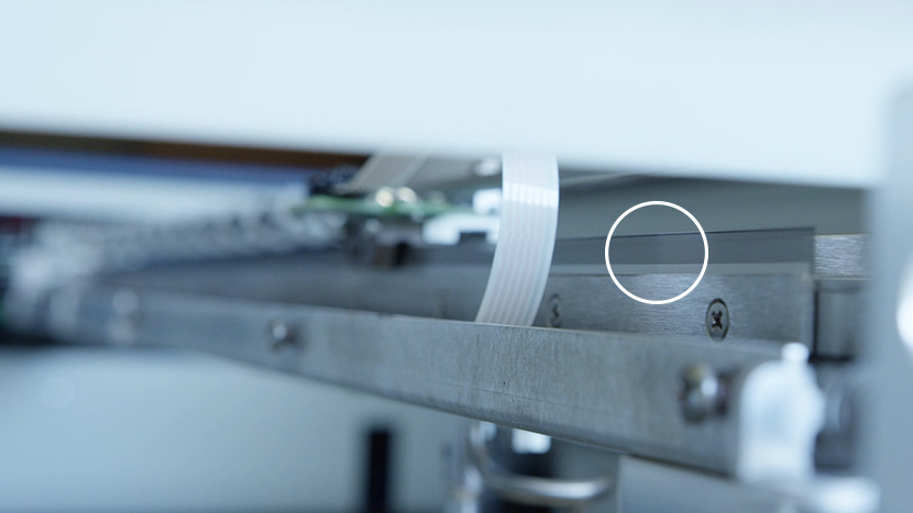 The encoder strip is the tinted transparent film running the length of the X-Axis. Close-up of the linear encoder strip.