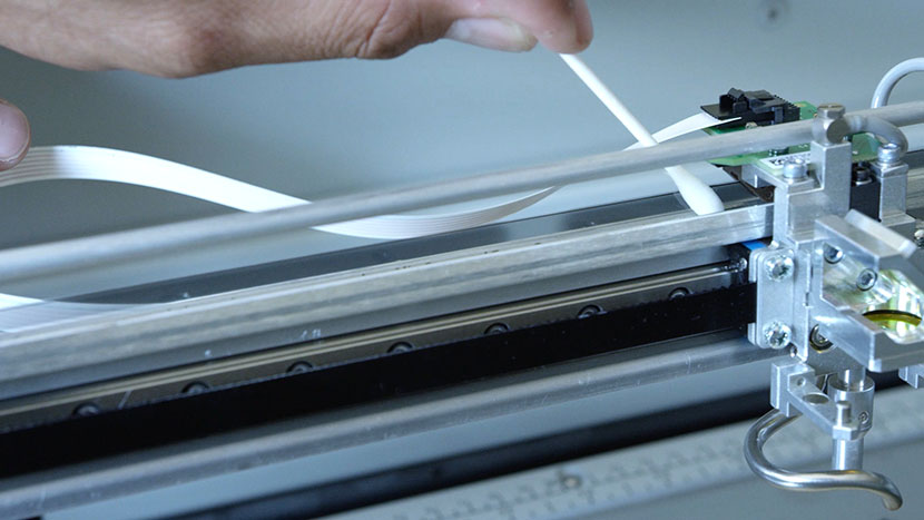 Run the cotton swab along the front of the encoder strip. Using a cotton swab to clean the front of the linear encoder strip.