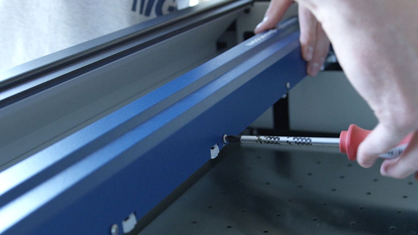 Tighten all of the X-Axis Assembly cover screws. Screwing in a screw on the back of the X-Axis Assembly.