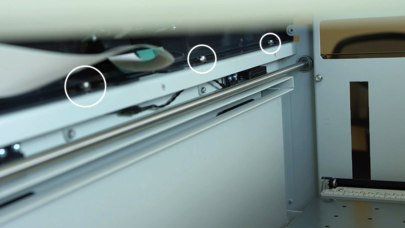 Loosen the four nuts that secure the bezel to the front of the machine The nuts holding down the bezel