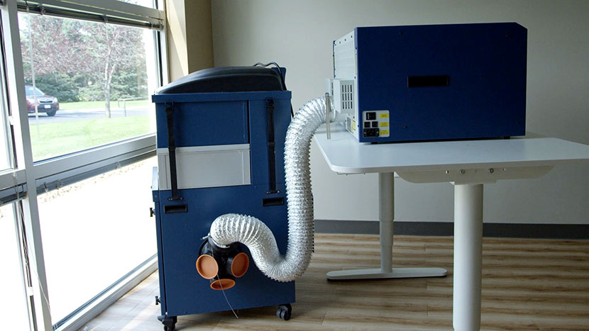 You can also hook up your laser system to an external filtration unit. The Epilog Laser Mini hooked up to an external filtration unit.