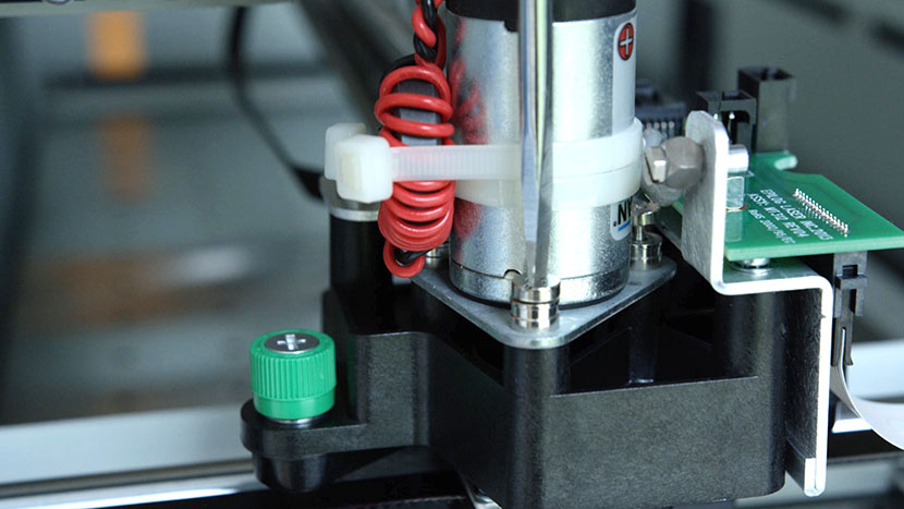 Unscrew the captive motor mounting screws. Unscrewing one of the captive screws securing the X-Motor.