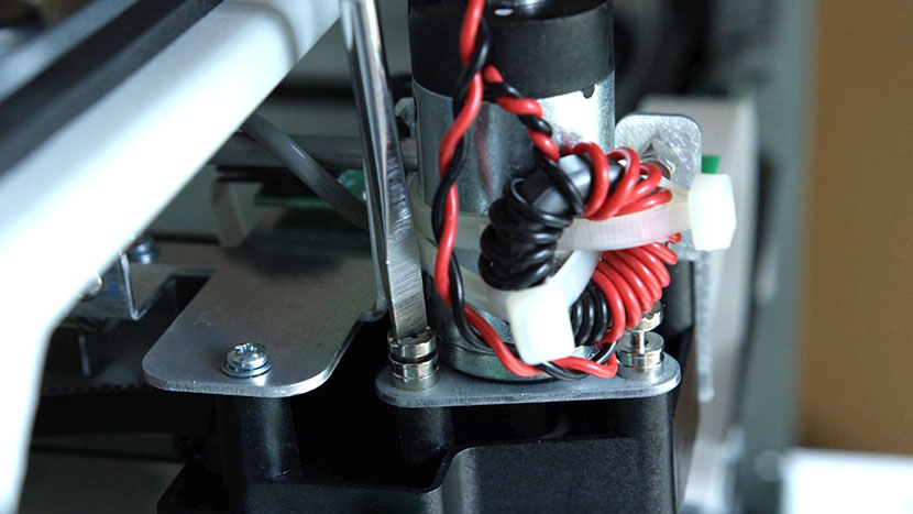 Unscrew the captive motor mounting screws. Unscrewing one of the captive screws securing the X-Motor.