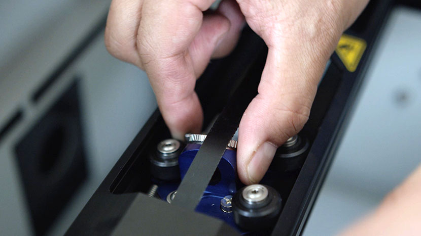 Remove the lens carriage by pinching the lever, tilting back, and lifting it up and out. Removing the lens carriage from the X-Axis Assembly.