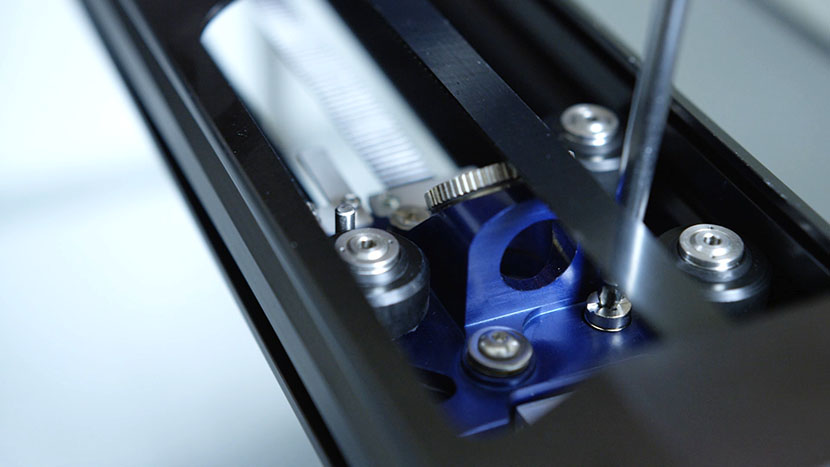 Tighten the two screws to secure the lens assembly to the belt assembly. Tightening the screws on the lens assembly.