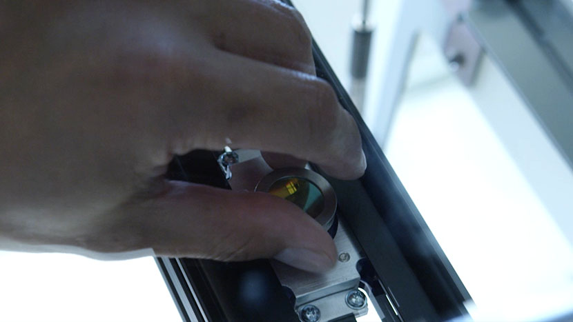 Unscrew the lens from underneath the carriage. Unscrewing the lens from the lens assembly.