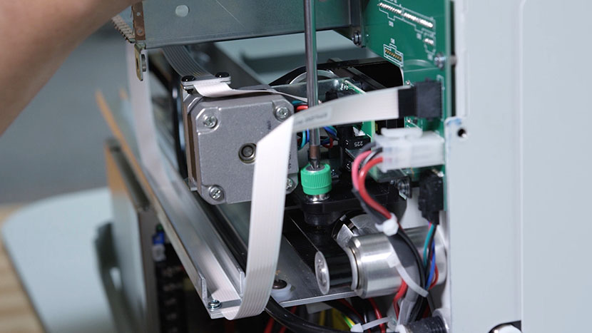 Loosen the back green captive screw. Unscrewing the x-axis assembly's back right green captive screw.
