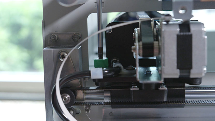 Loosen the front green captive screw. Unscrewing the x-axis assembly's front right green captive screw.