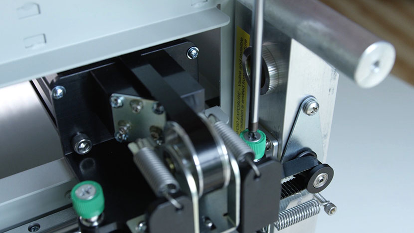 Loosen the back green captive screw. Unscrewing the x-axis assembly's back left green captive screw.