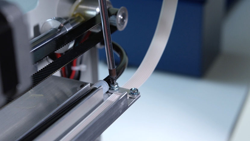 Install the clamp over the white ribbon cable. Screwing in the ribbon cable clamp.