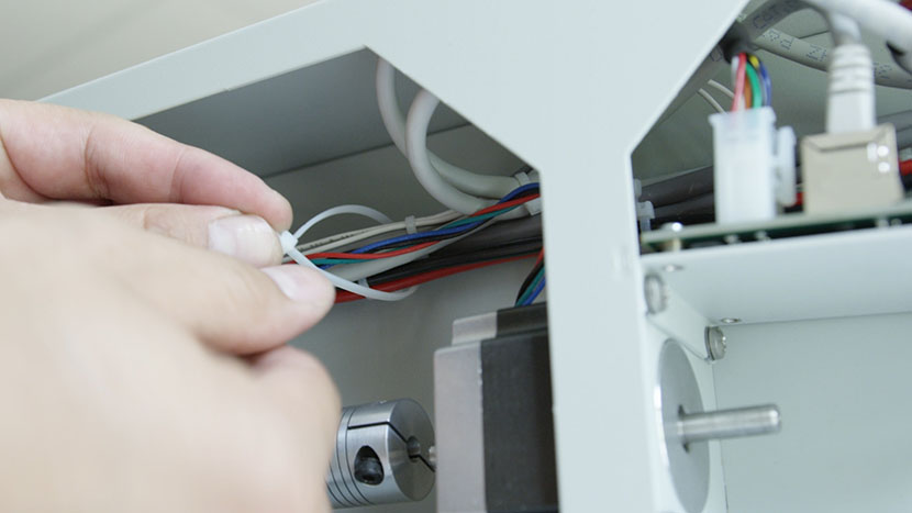 Attach new zip ties to hold the cables together. Securing a new zip tie around the rear compartment wires.