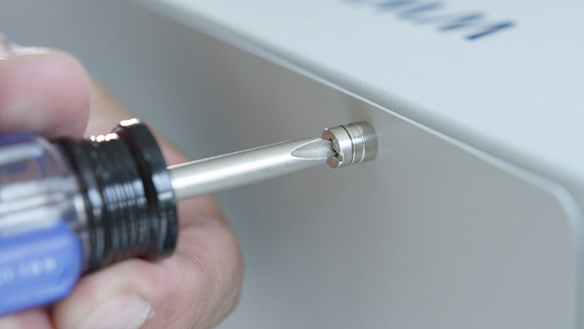 Tighten the rear panel's two screws. Screwing in the rear panel's top right screw.